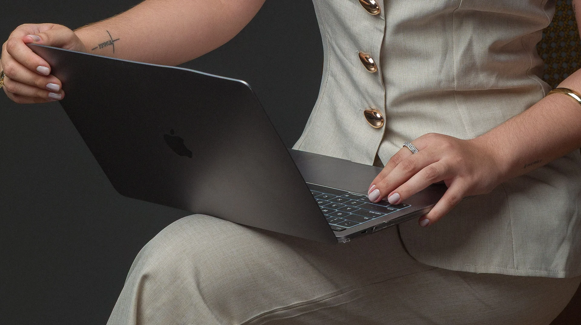 Mãos digitando em um notebook apoiado no colo