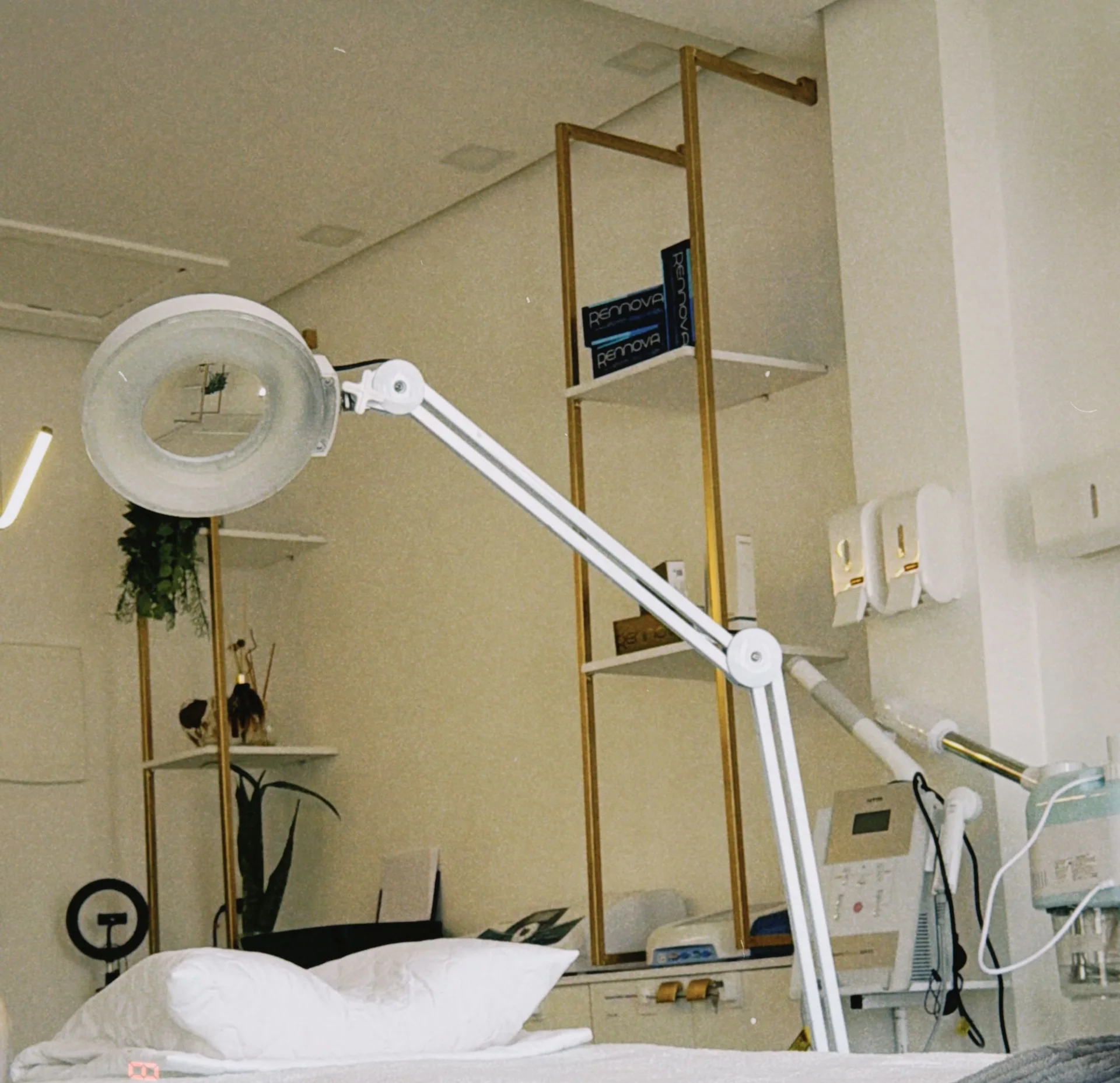 Sala de atendimento com maca, lupa de luz e estante dourada